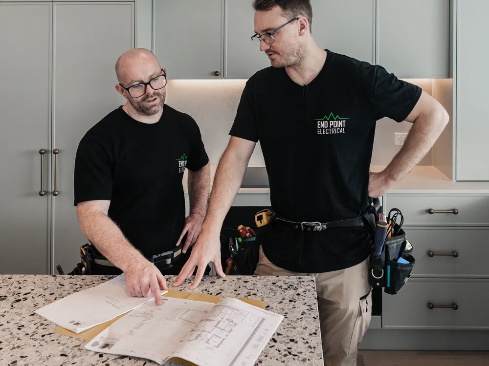 Two End Point Electrical electricians reviewing plans on a kitchen benchtop